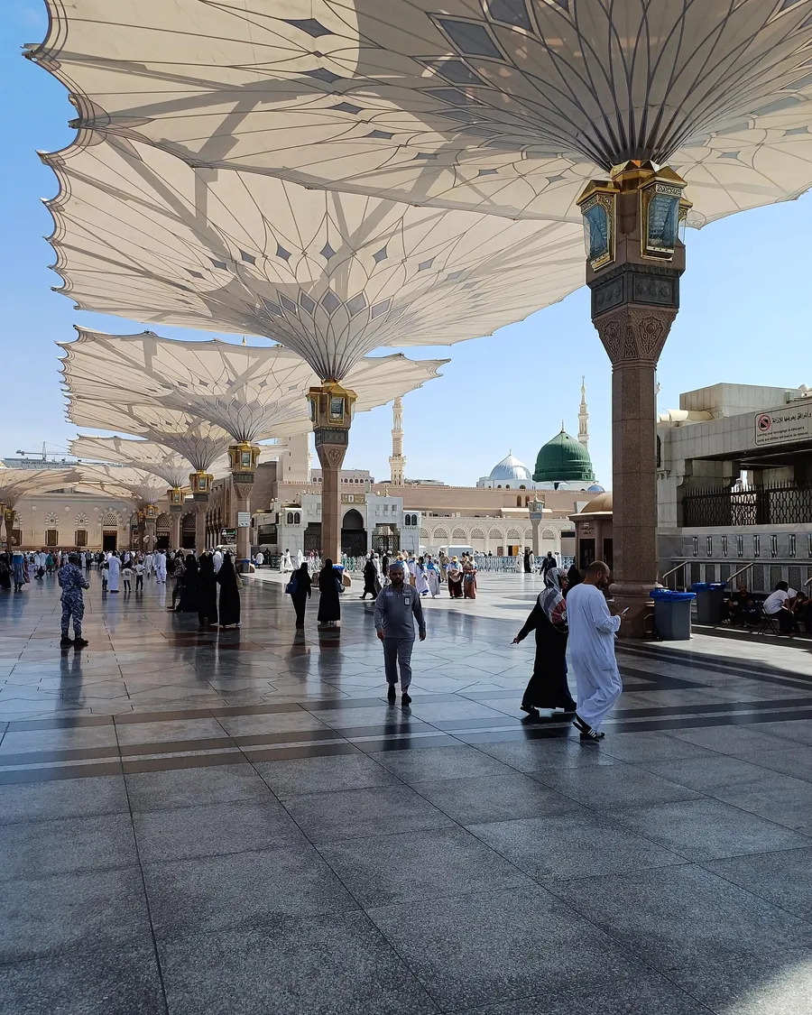 Pilgrims crossing the courtyard of Al-Masjid an-Nabawi under its shade canopies